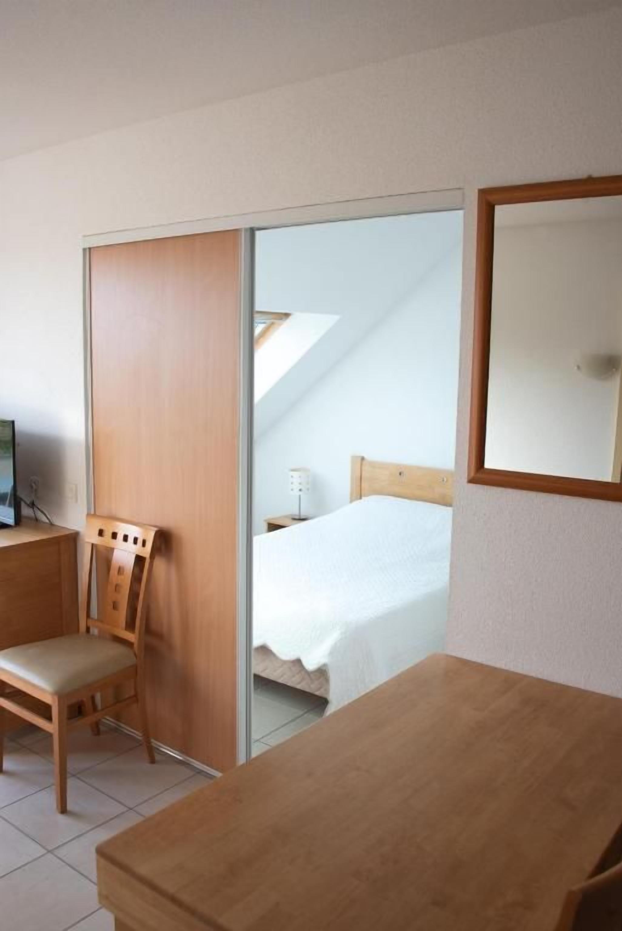 A room with a bed, a desk, a chair, and a sliding door.