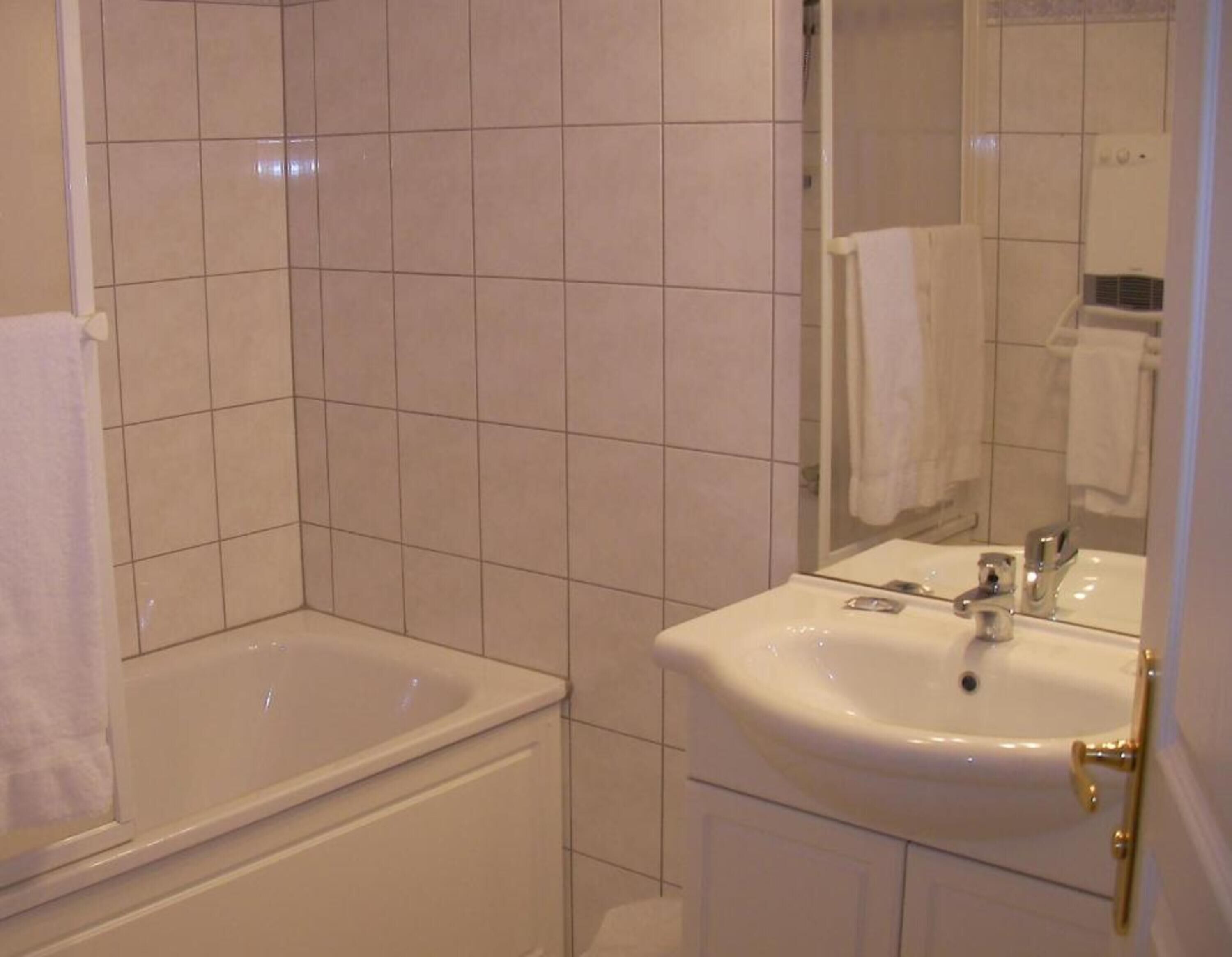 A bathroom with a bathtub, a sink, and a mirror.
