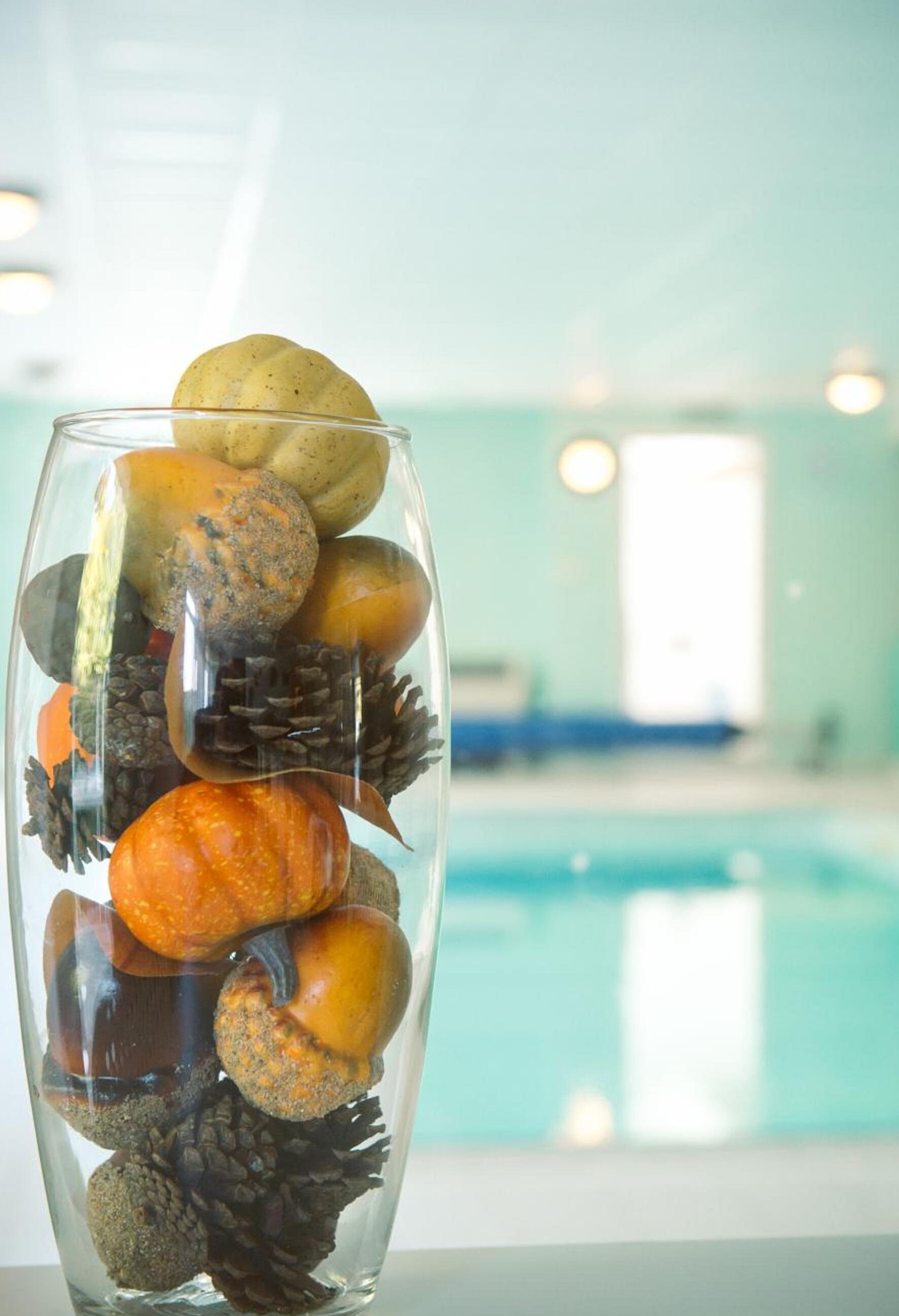 A clear glass vase with a variety of natural elements like stones, pine cones, and a pumpkin.