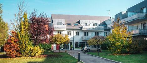 A multi-story residential building with a parking area and a driveway leading to the entrance.