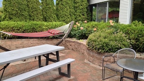 A patio area with a hammock, picnic table, and chairs. - Parkside Inn Bridgeview (Mackinaw City)