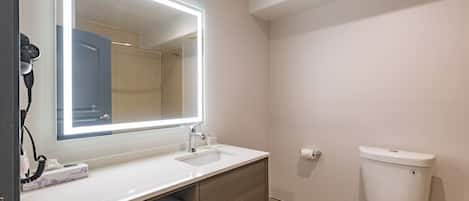 Un baño moderno con un espejo grande, un lavabo, un inodoro y un perchero para toallas.