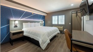 Moderni hotellihuone, jossa on suuri sänky, työpöytä ja televisio.