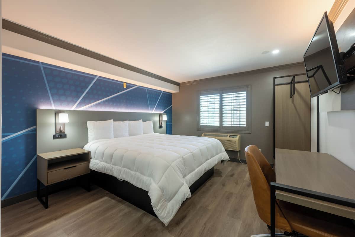 Ein modernes Hotelzimmer mit einem großen Bett, einem Schreibtisch und einem Fernseher.
