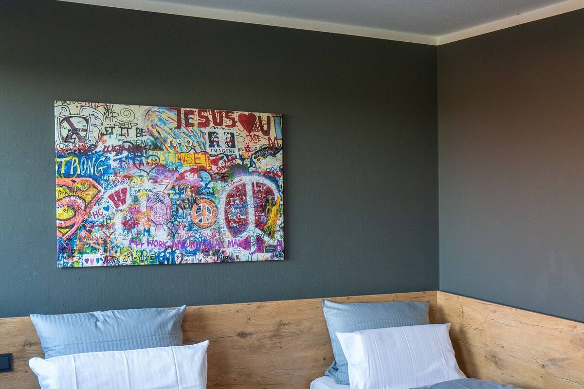 A room with two wooden beds, each with a headboard, and a colorful graffiti wall.