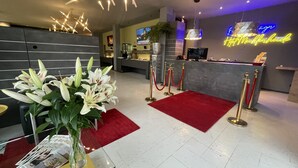 A hotel reception area with a modern design, featuring a reception desk, red carpet, and a neon sign. - Hotel Mecklenheide Hannover (Hannover)