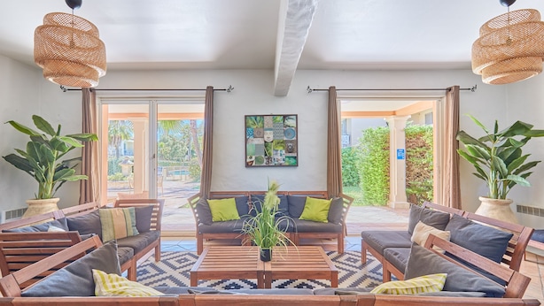 A spacious indoor seating area with wooden furniture and woven ceiling lights. - Résidence Odalys La Palmeraie (Grimaud)
