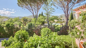 A lush garden with tall trees and a pool in the background. - Résidence Odalys La Palmeraie (Grimaud)