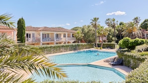 A pool area with a clear blue pool, lounge chairs, and a building with balconies. - Résidence Odalys La Palmeraie (Grimaud)