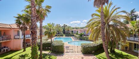 A resort with a swimming pool, palm trees, and a brick pathway.