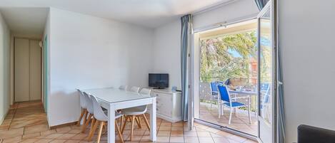 A modern room with a dining table, chairs, a TV, and a sliding glass door leading to an outdoor patio.