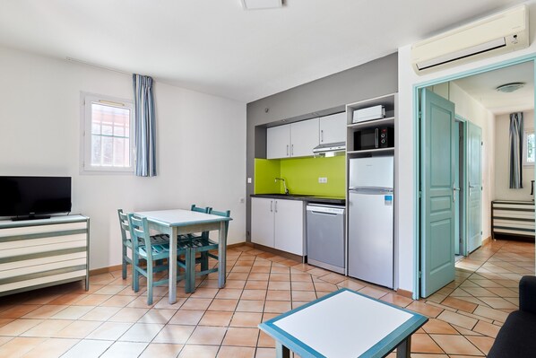 Une cuisine compacte comprenant un coin repas, un téléviseur et une petite table.