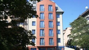 Ett hotell med flera våningar, en röd och vit fasad, balkonger och en klarblå himmel.