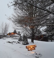 Paisaje nevado con un cartel de 'Welcome' y un edificio al fondo.