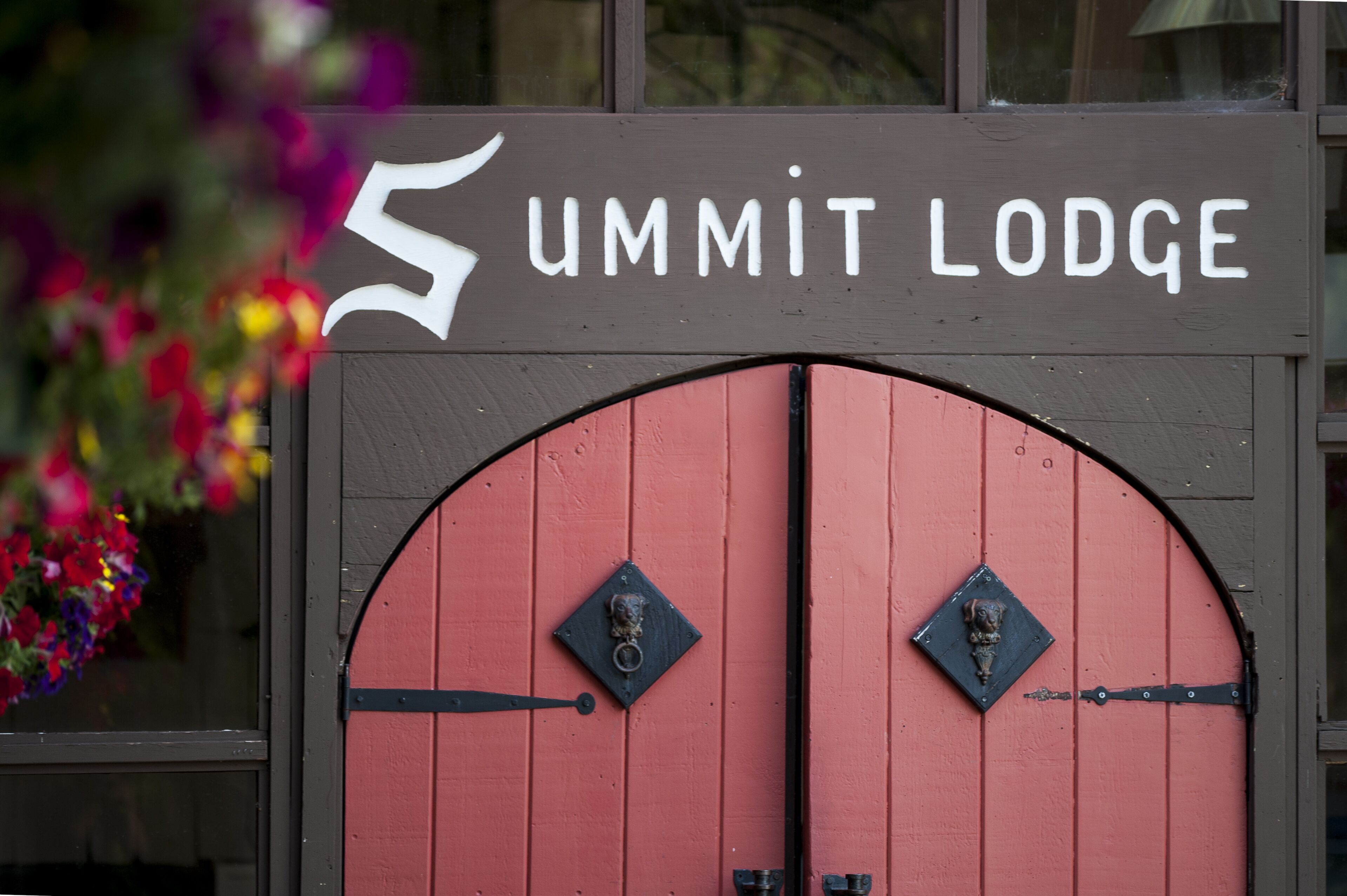 A sign for 'Summit Lodge' with a red door and two metal knockers.