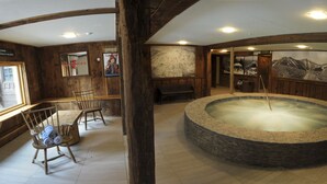 A rustic interior with a stone hot tub, wooden furniture, and a mountain mural. - Summit Lodge (Killington)