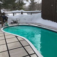 Una piscina con borde de baldosas y valla de madera.