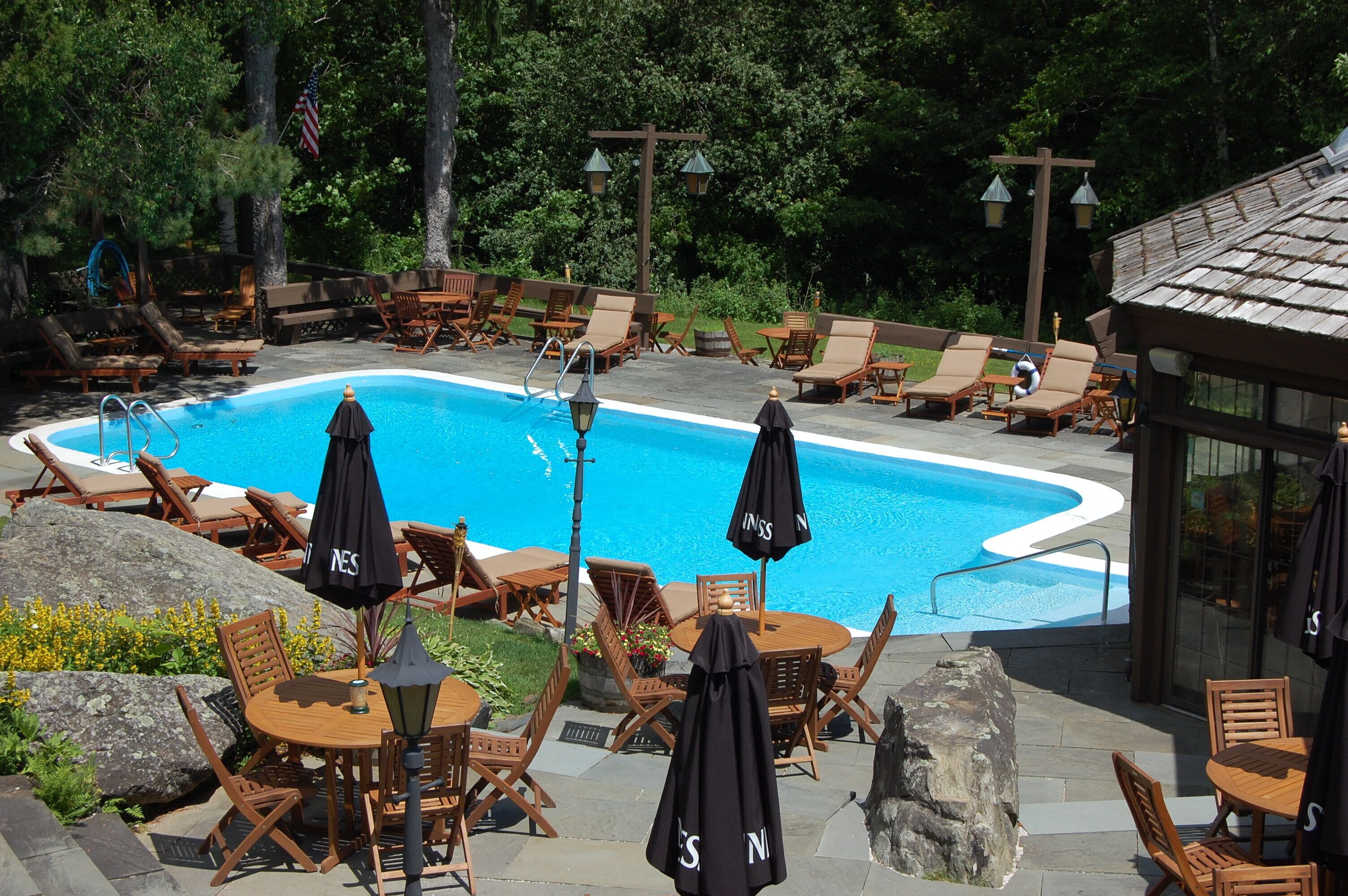 A poolside area with lounge chairs, umbrellas, and a wooden deck.