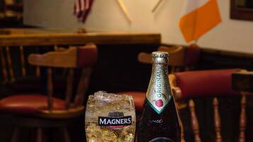 A glass of MAGNERS Irish cider and a bottle of MAGNERS Irish cider on a wooden table in a pub with a sign reading "Pub House".