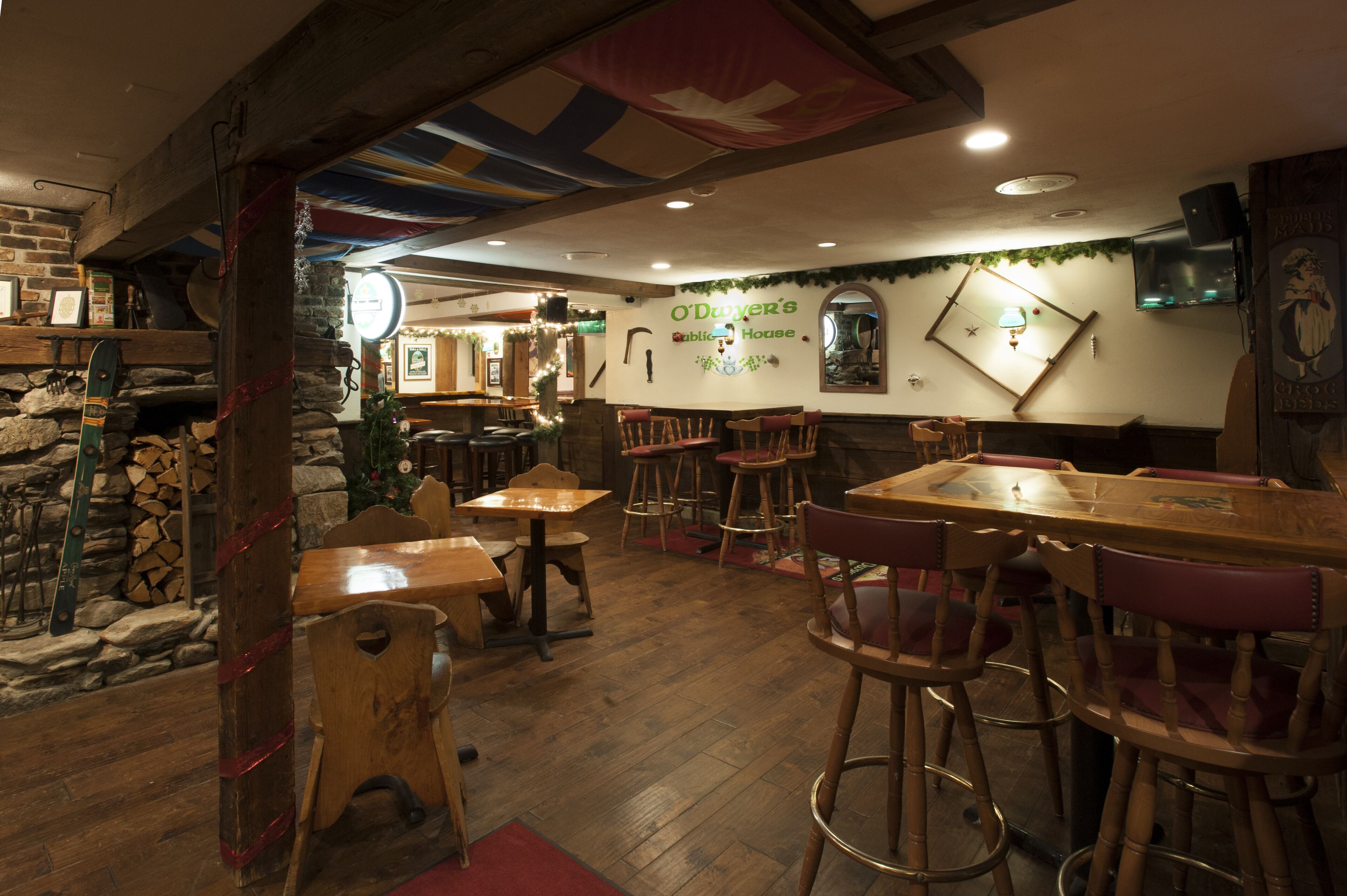 A rustic interior with wooden tables and chairs, stone walls, and a fireplace.