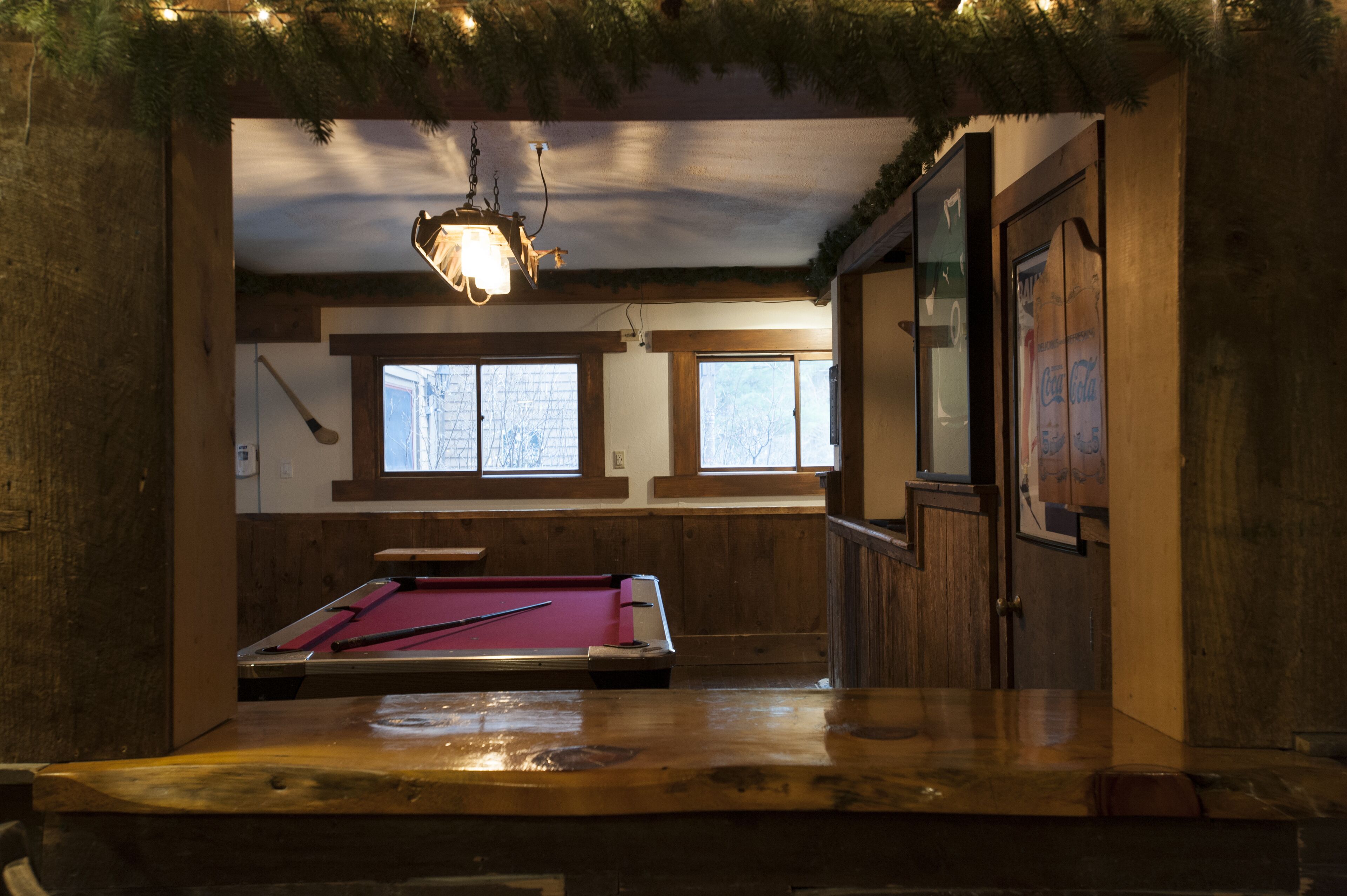 A pool table in a room with wooden walls and windows.