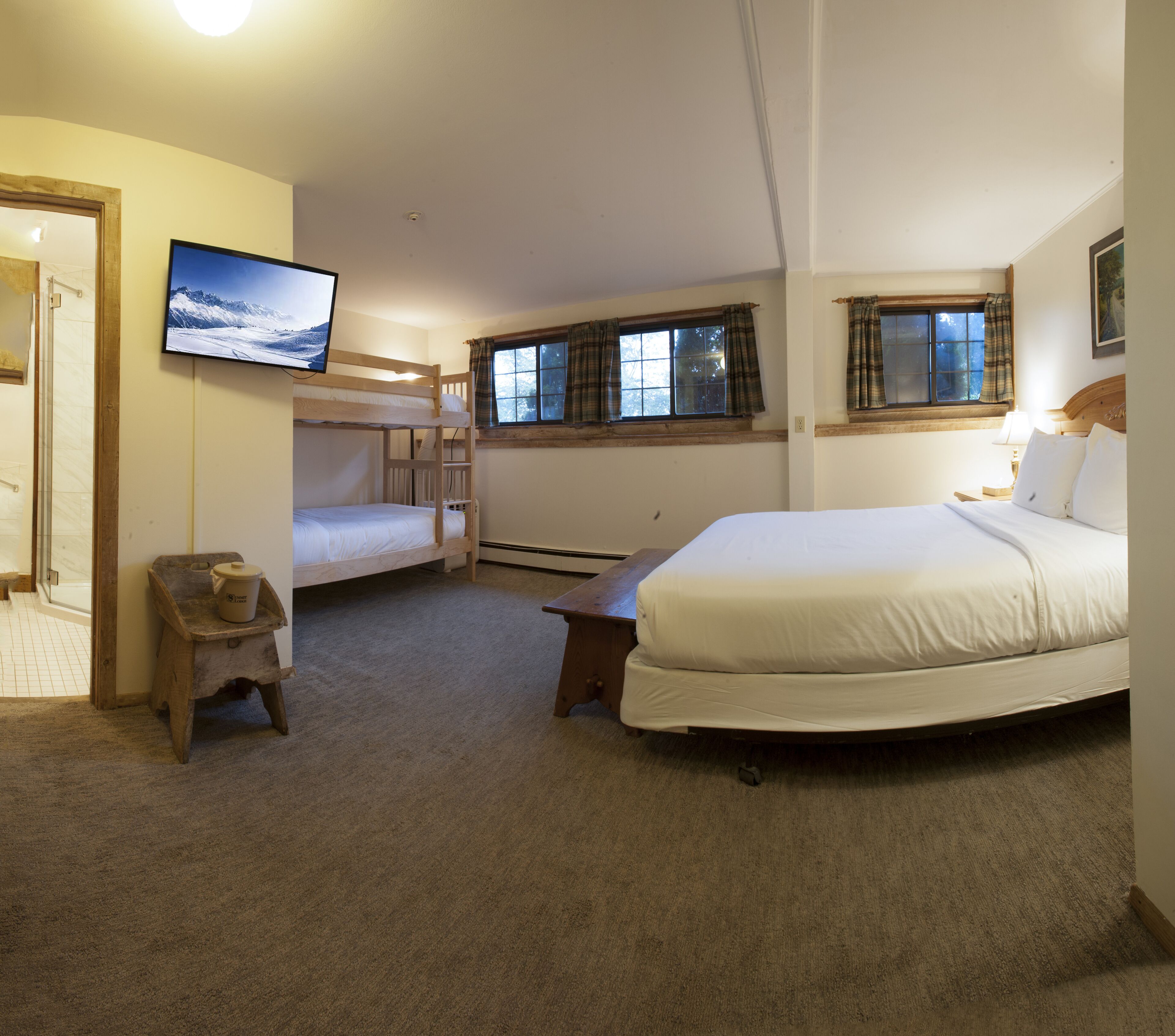 A bedroom with a bunk bed, a single bed, a television, a small table, and a window with curtains.