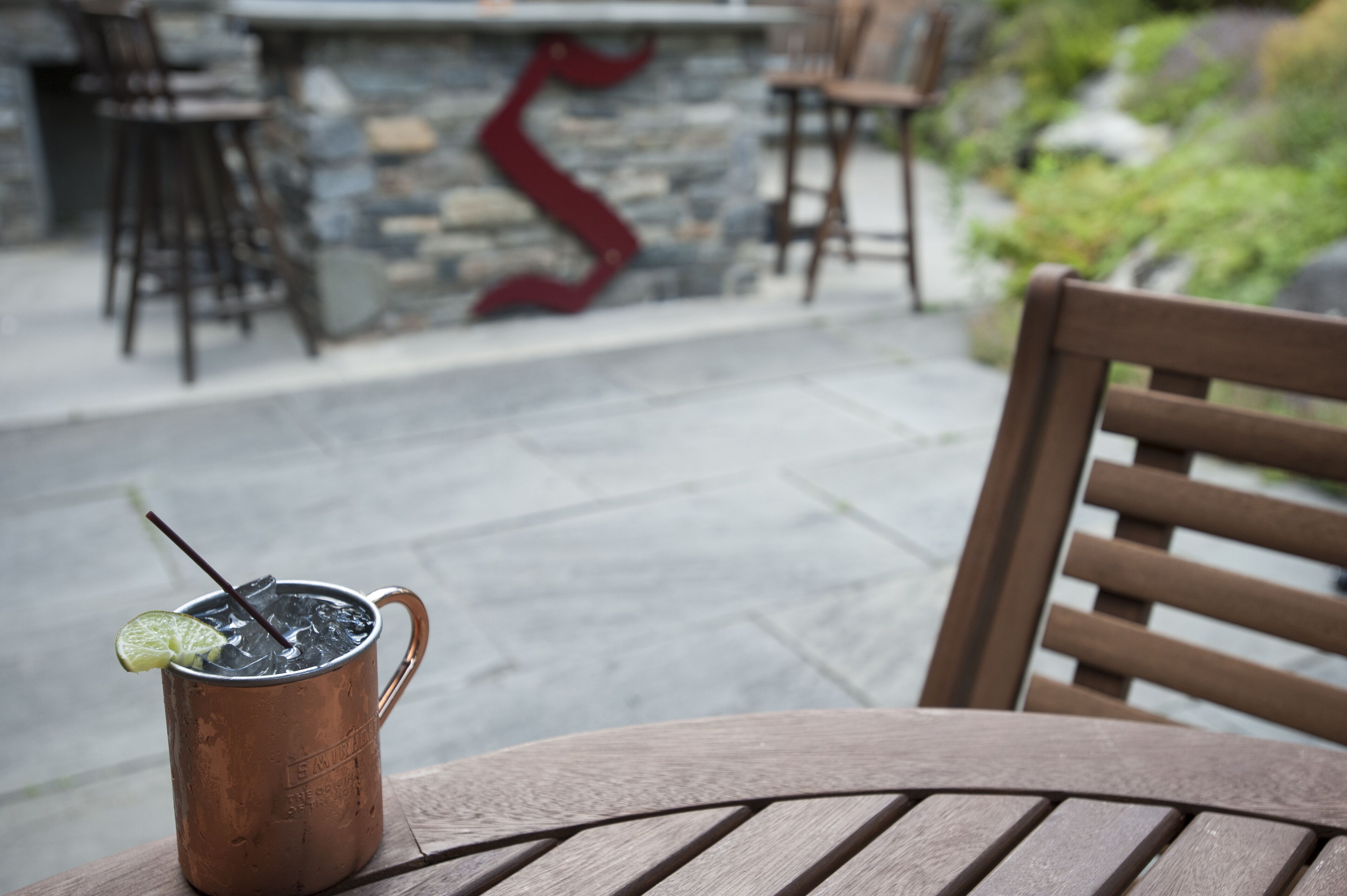 A copper mug with a straw and lime on a wooden table.