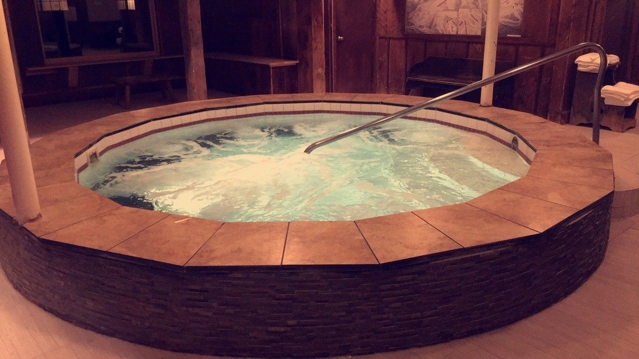 A circular hot tub with a metal railing, surrounded by stone tiles.