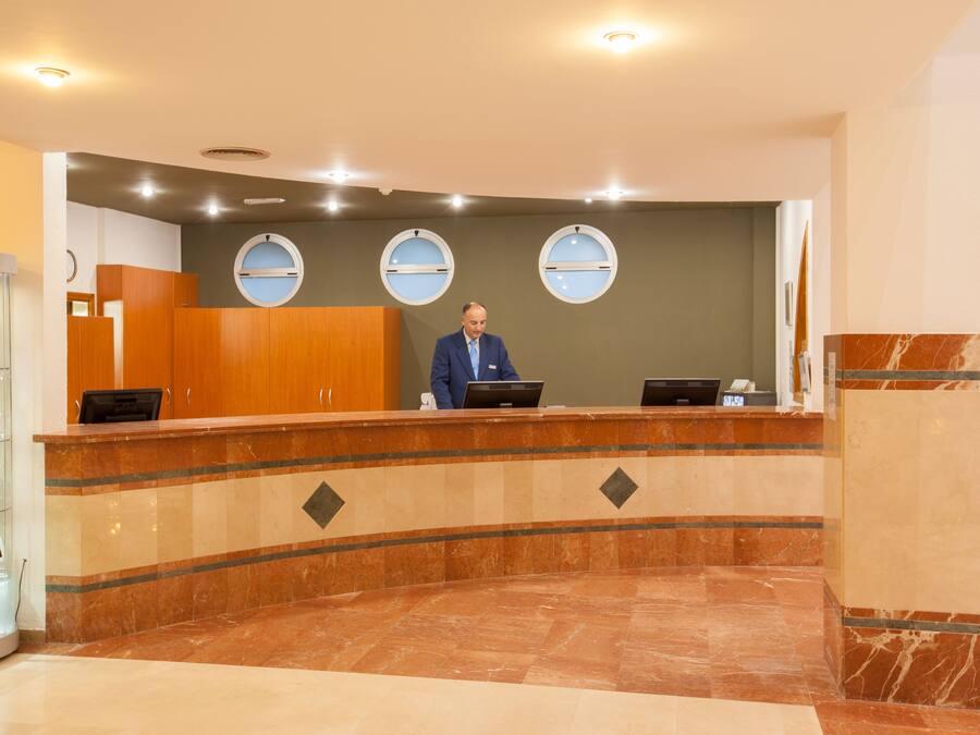 Un espace d’accueil doté d’un comptoir en marbre incurvé, de meubles en bois et de trois fenêtres rondes.