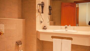 A bathroom with a toilet, sink, and hairdryer mounted on the wall.