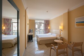 A hotel room with two beds, a desk with a chair, a small table, and a view of the outside. - IFA Altamarena by Lopesan Hotels - All Inclusive (Pajara)