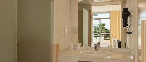 A modern bathroom with a large mirror, a sink, and a hairdryer mounted on the wall.
