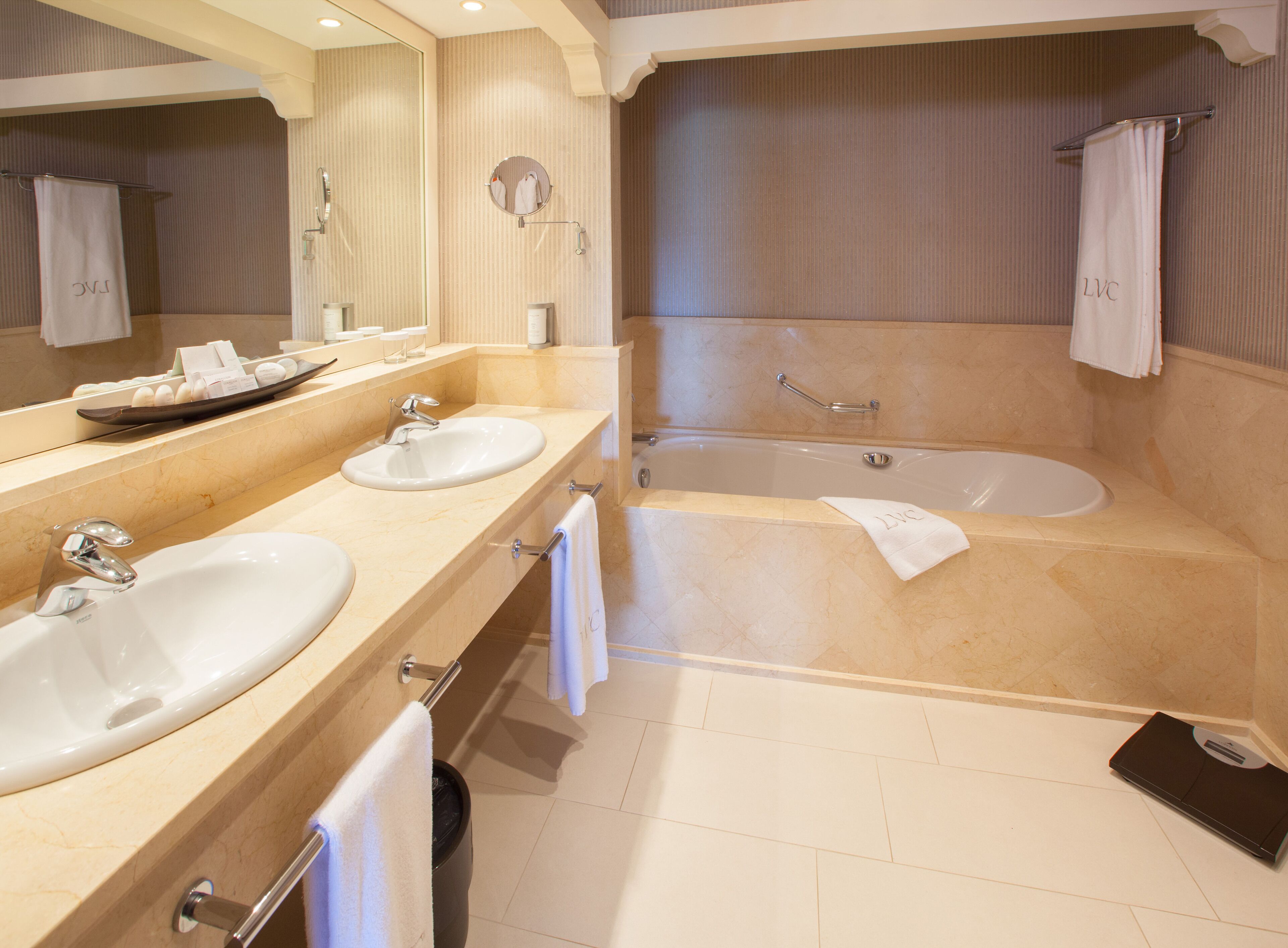 A modern bathroom with two sinks, a bathtub, and a large mirror.