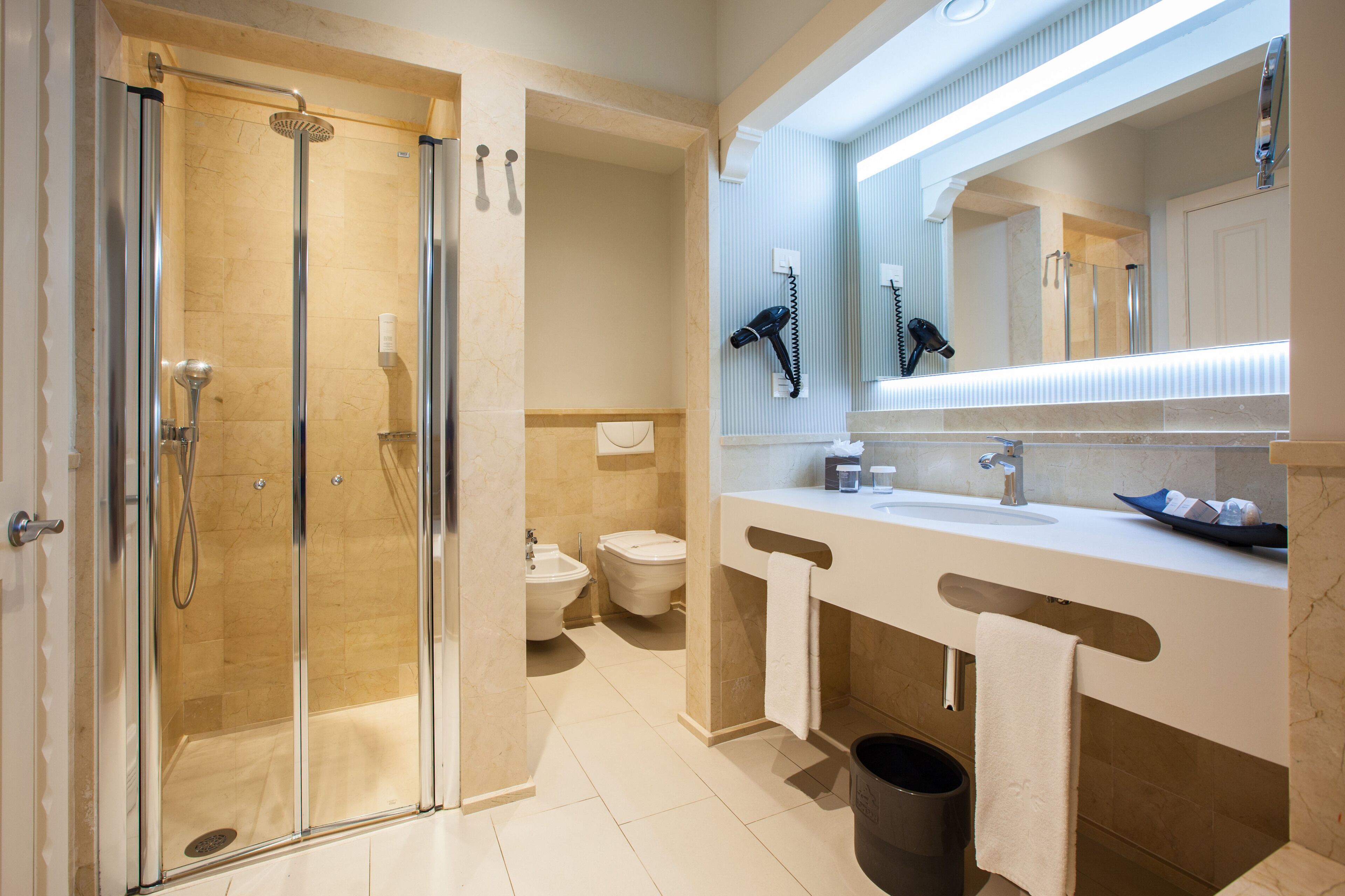 A modern bathroom with a glass-enclosed shower, a double sink vanity, and a large mirror.