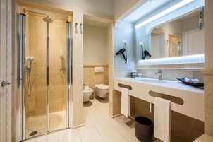 Ein modernes Badezimmer mit einer Duschkabine, einem Doppelwaschbecken und einem großen Spiegel.