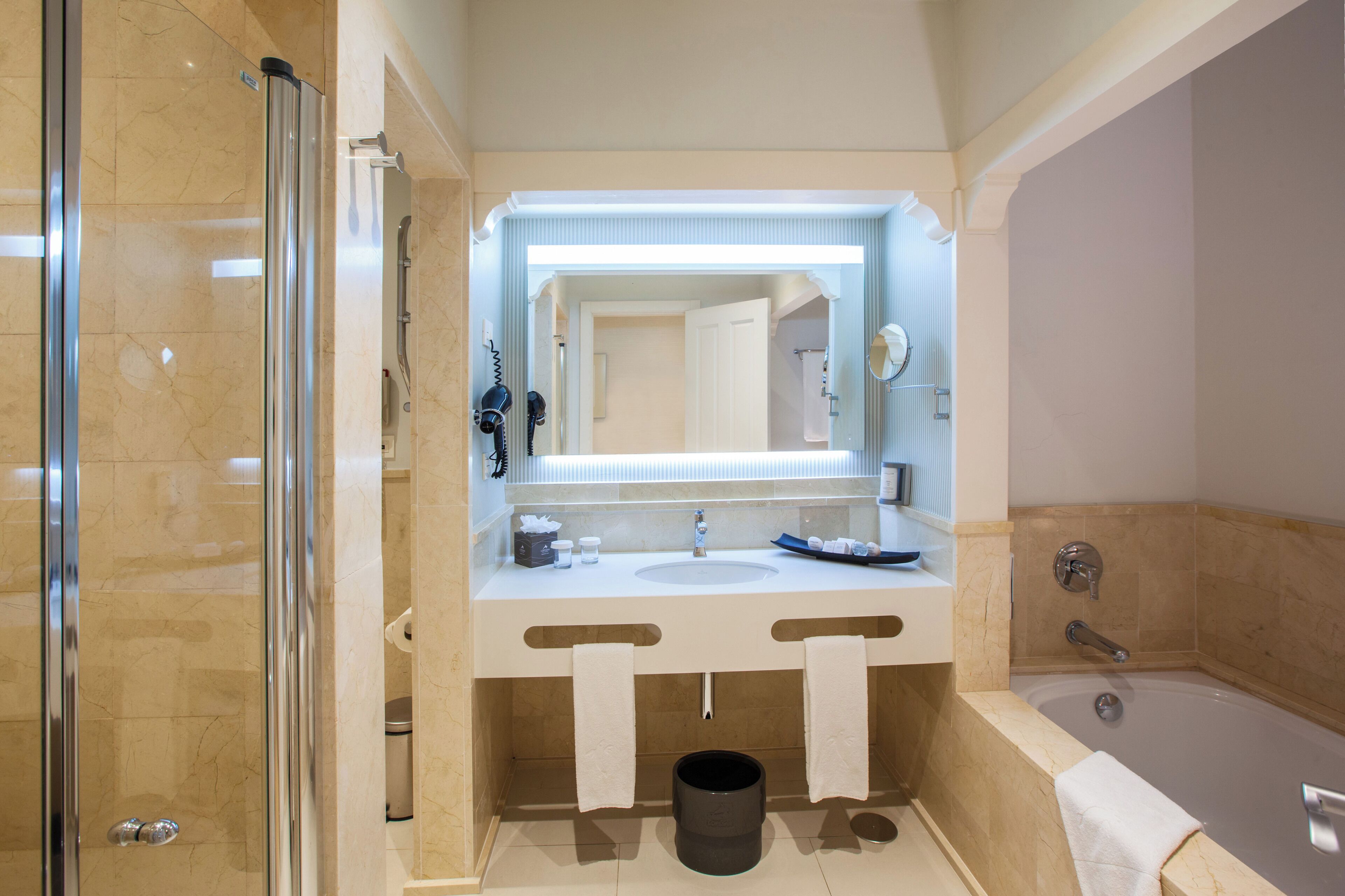 Un baño moderno con ducha de vidrio, un espejo grande y una bañera.