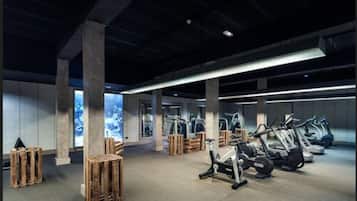 Een fitnessruimte met trainingsapparatuur, houten pallets en grote ramen.