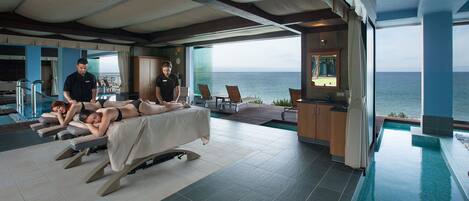 A spa area with massage tables, a pool, and a view of the ocean.