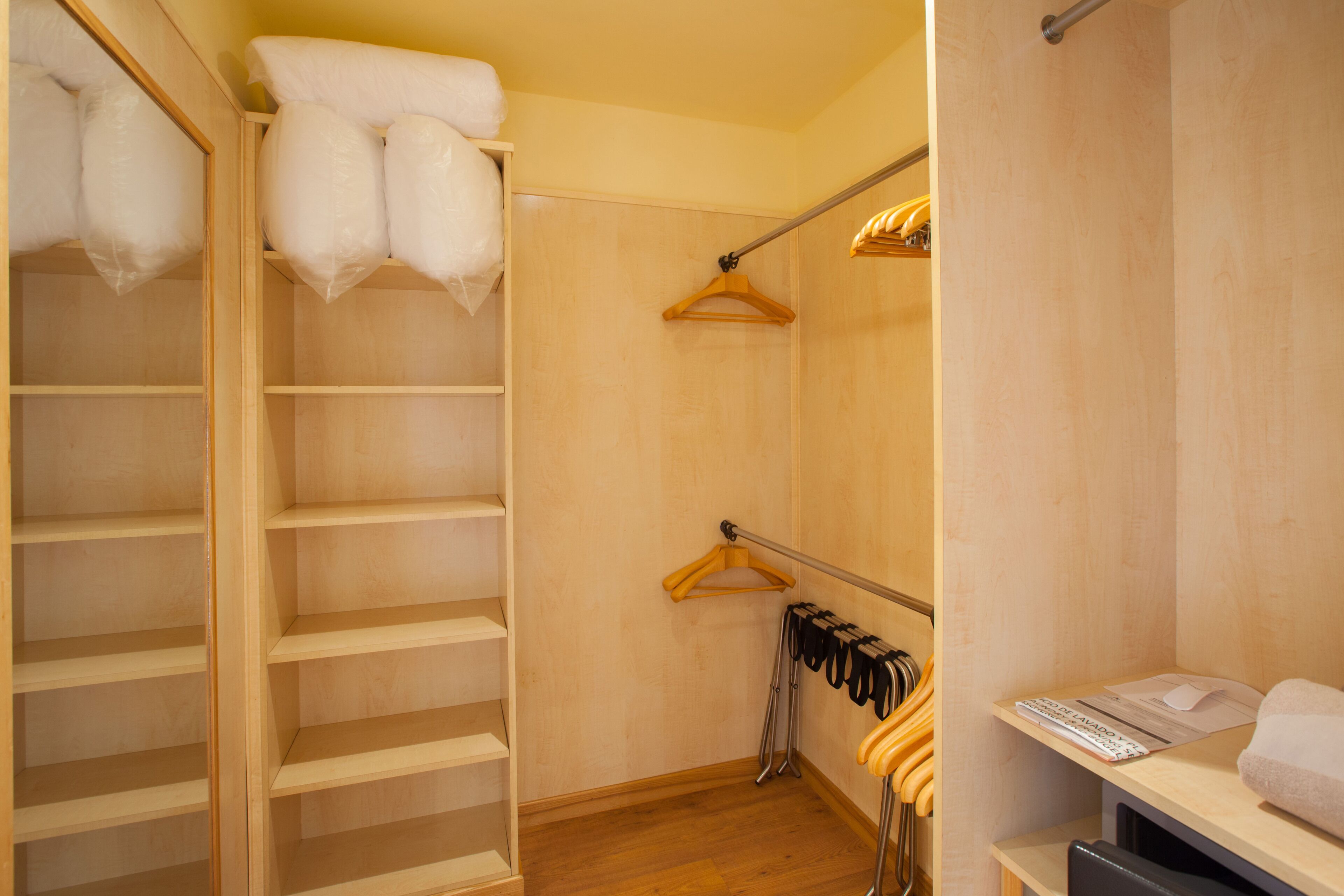 Ein begehbarer Kleiderschrank mit Holzböden, einer Kleiderstange und einer Sitzbank mit Handtuch.