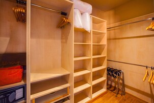 A closet with open shelves, a hanging rack, and a microwave.