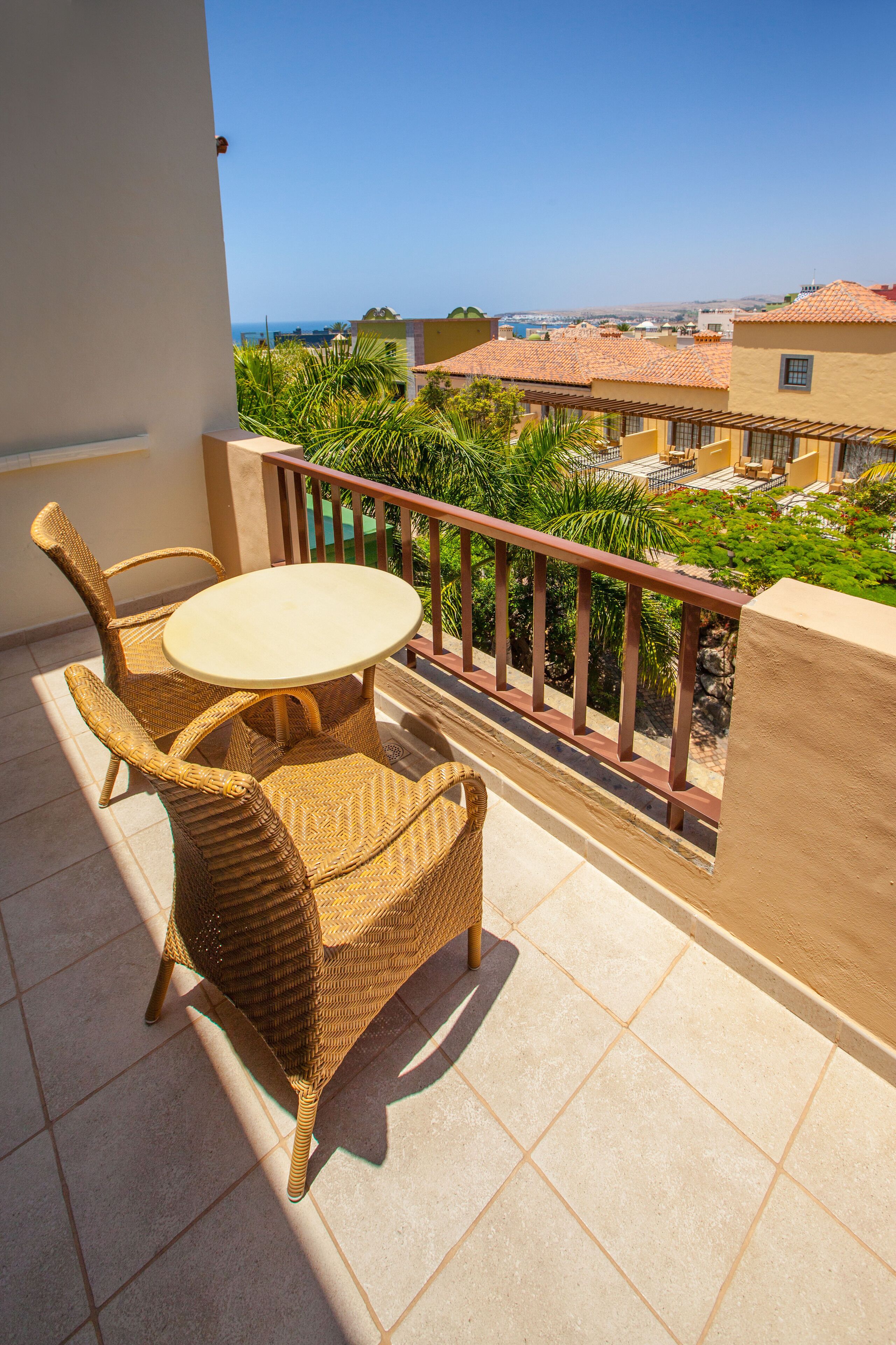 A balcony with wicker furniture and a view of a residential area.