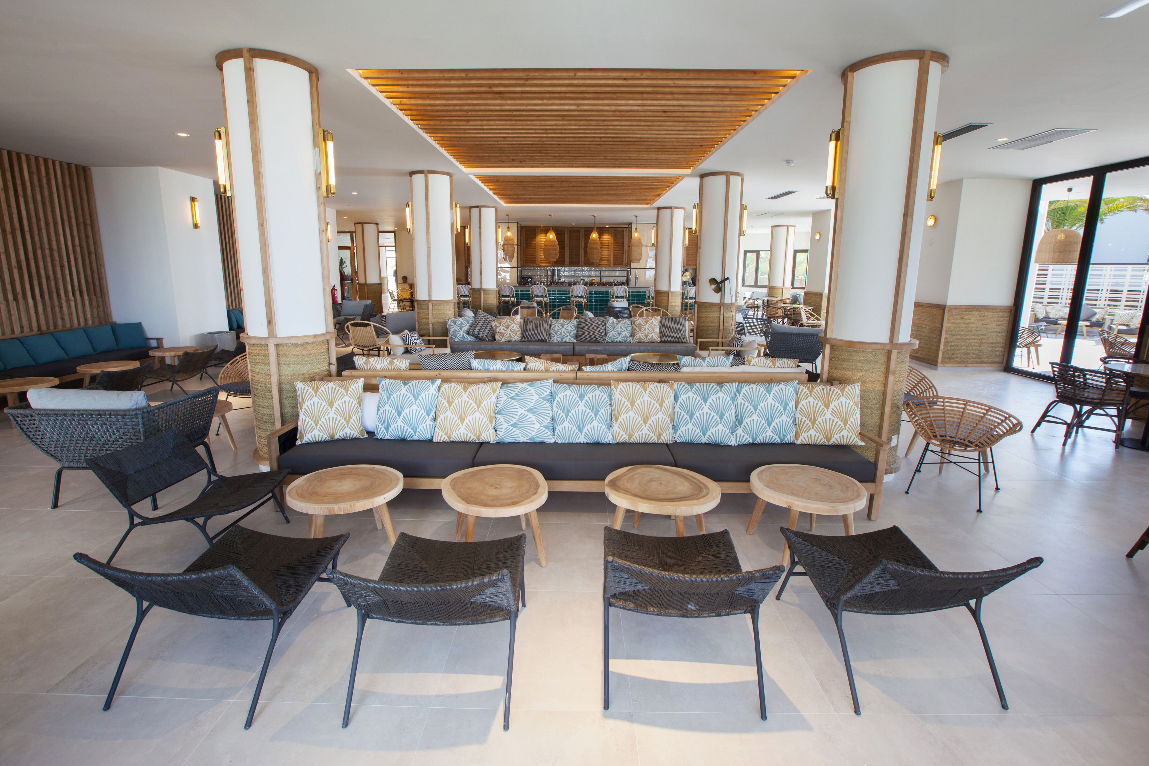 A spacious lobby with a central seating area, a bar, and a view of the kitchen.