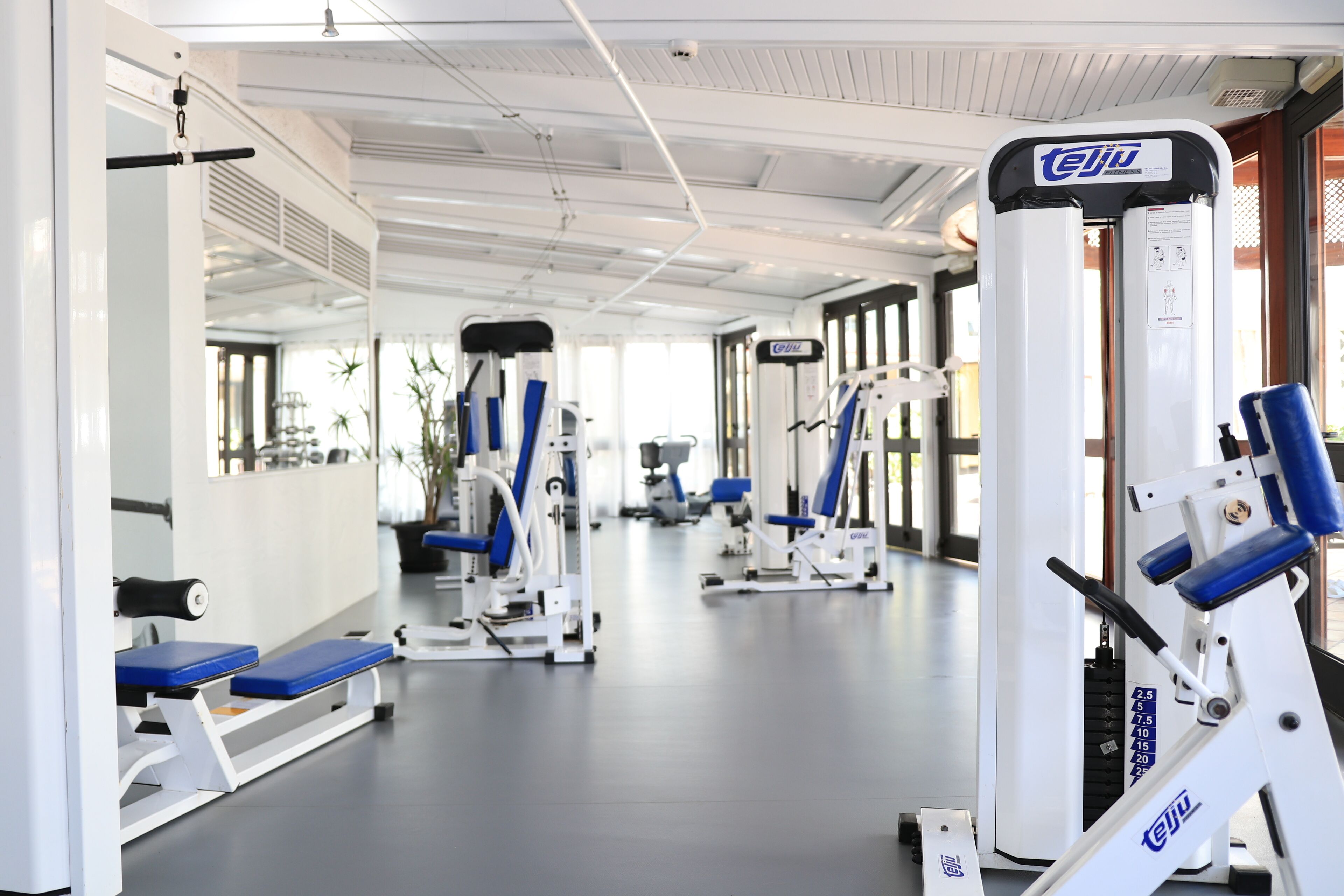 Ein Fitnessstudio mit verschiedenen Trainingsgeräten, darunter eine Beinpresse und eine Brustpresse.