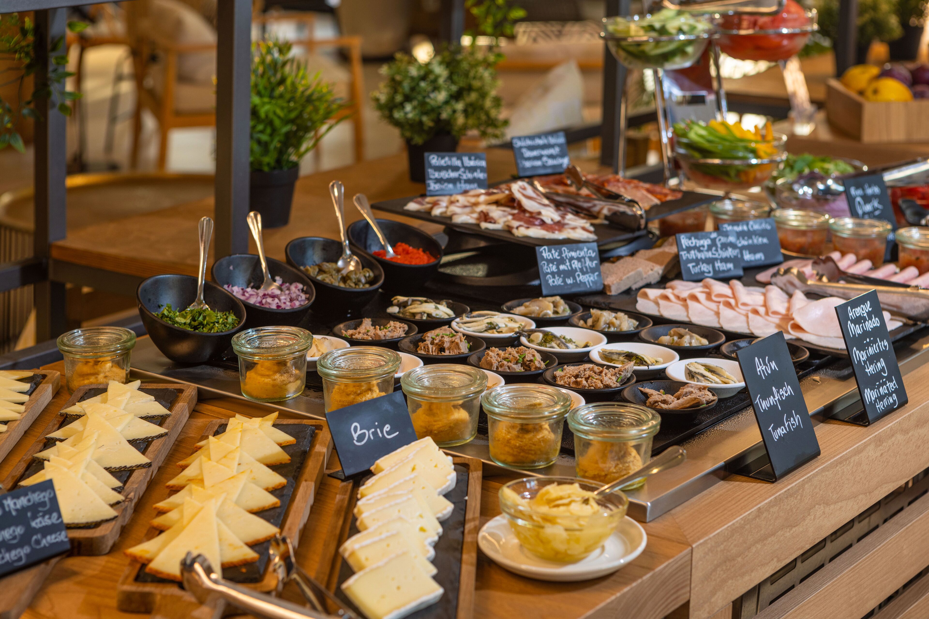 A buffet with various food options including cheeses, meats, and salads.