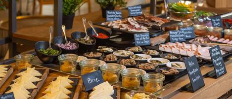 A buffet with various food options including cheeses, meats, and salads.
