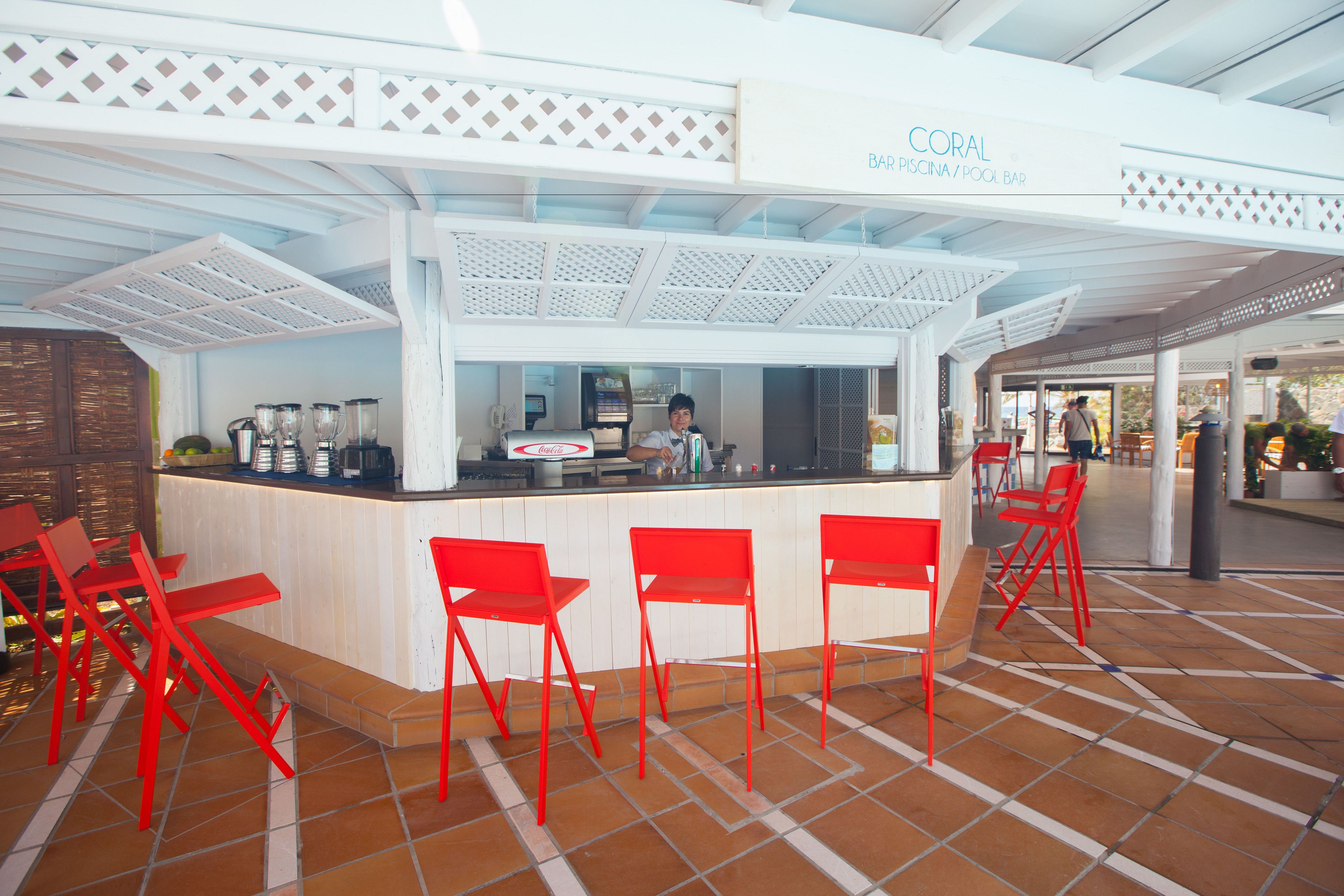 Una zona de bar con mostrador, sillas rojas y un letrero que dice 