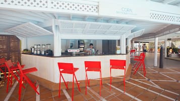 Una zona de bar con mostrador, sillas rojas y un letrero que dice