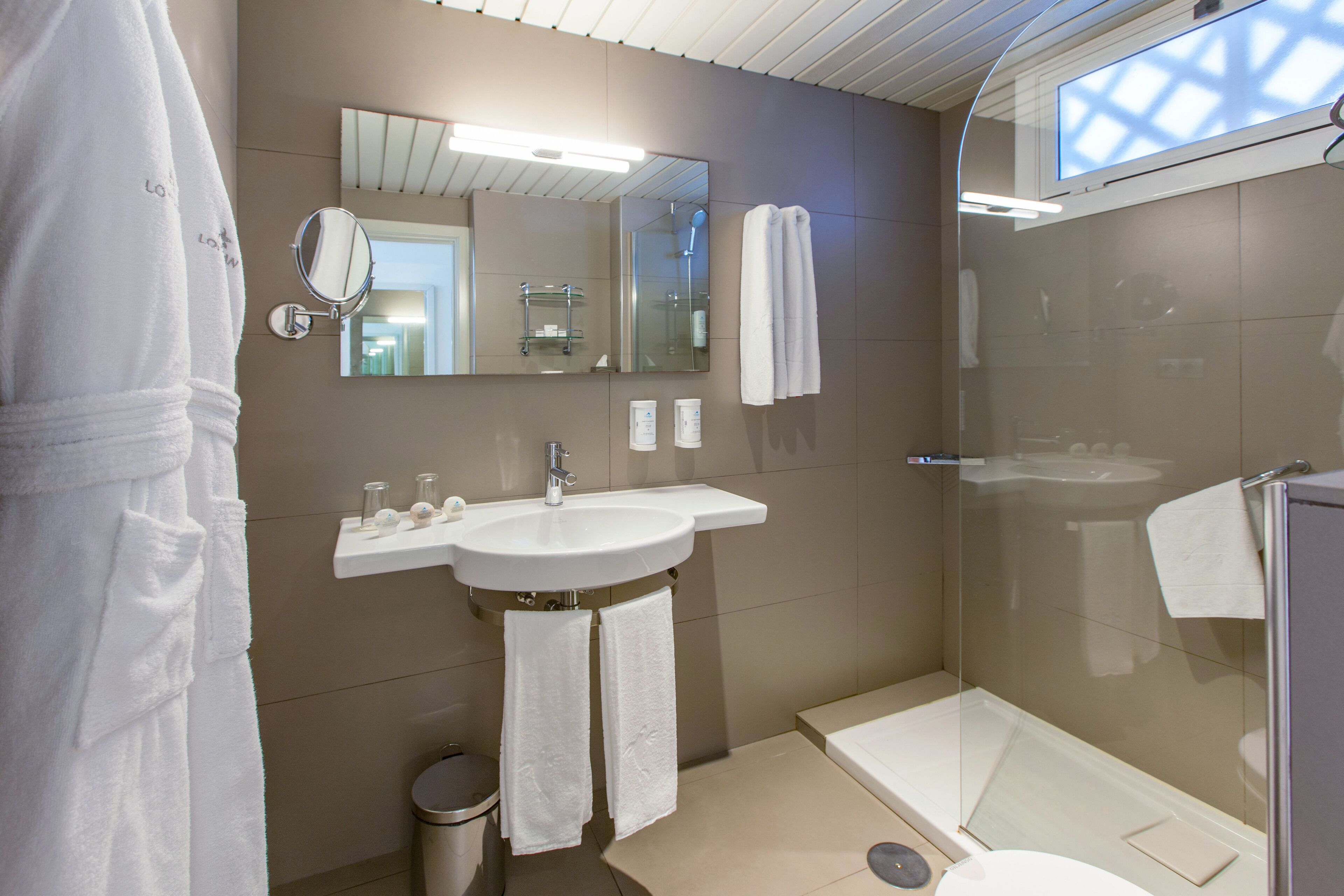 A modern bathroom with a sink, mirror, and glass-enclosed shower.