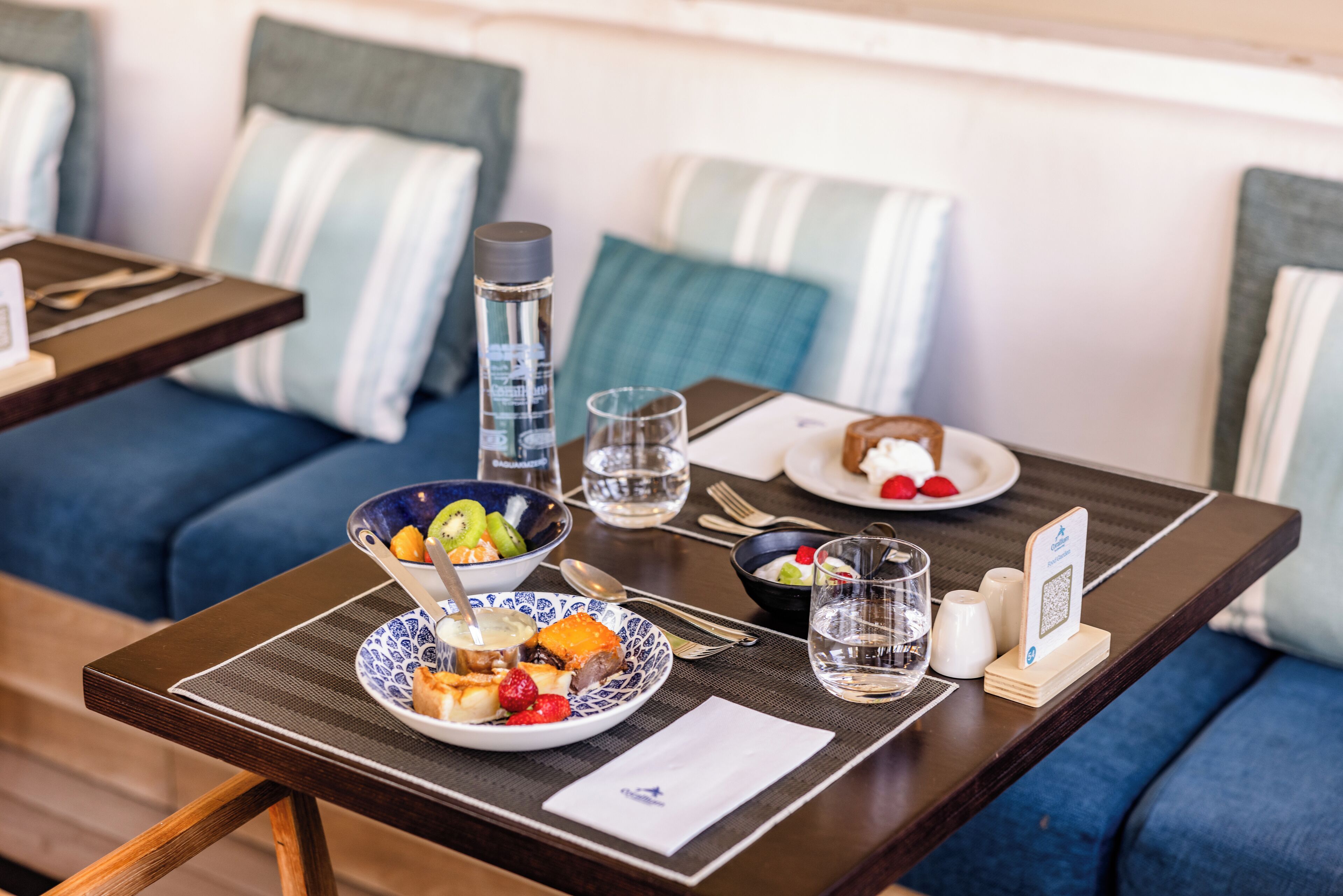 A dining table with a bowl of fruit, a plate of food, a glass of water, and a salt and pepper set.