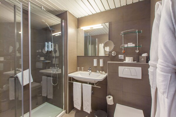 Un baño moderno con ducha de vidrio, un lavabo blanco y un espejo encima.